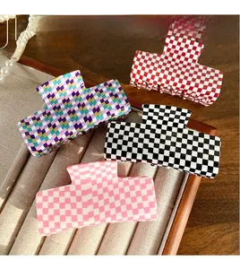 Detail of four checkered acrylic hair claws in assorted colors on a velvet tray