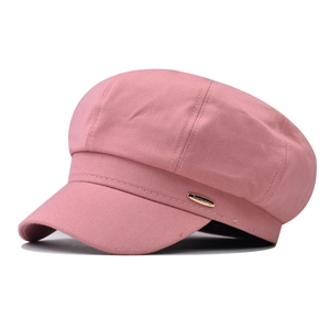 Detailed side view of pink octagonal baker boy hat featuring a gold metallic logo plate