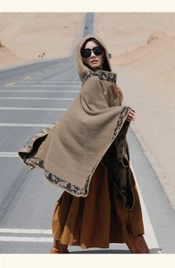 Ethnic hooded poncho in brown floral trim worn on a scenic desert highway background