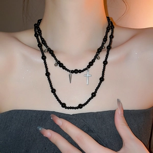 Detail of Y2K double-layer black beaded necklace with silver cross and cone pendants