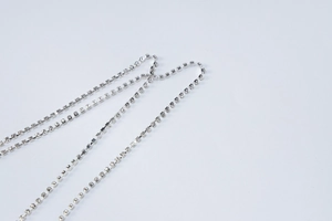Dettaglio ravvicinato di catene di strass argento con supporti metallici su abito da sera