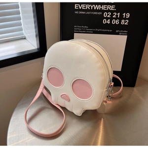 Skull shaped crossbody bag in white and pink PU leather on a minimalist metal table
