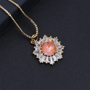 Detailed macro of gold plated sunflower necklace with orange gemstone and clear crystals