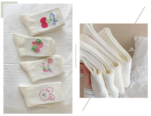 Detail of white cotton socks with embroidered cherry, strawberry, and rabbit patterns