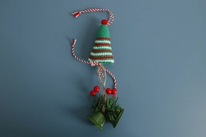 Detailed view of handmade knitted Christmas ornament with green bells and red berries