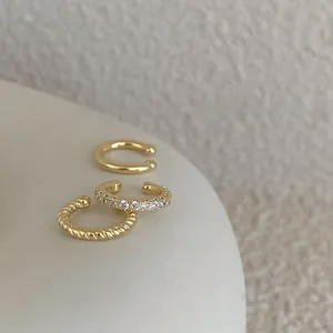 Vue macro d'un ensemble de 3 bagues d'oreille dorées avec motifs torsadés et zircons