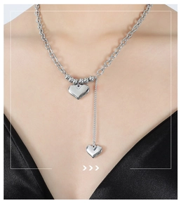 Close-up of double heart pendants on a silver metal chain worn by a model