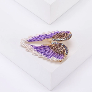 Macro detail of angel wing brooch featuring purple enamel and sparkling rhinestones