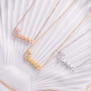 Three Queen crown pendant necklaces in rose gold, gold, and silver on a textured base
