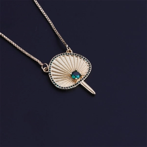 Collier éventail plaqué or avec pierres de zircon vert sur fond sombre style élégant