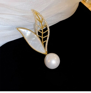 Detailed view of 18K gold leaf brooch with mother of pearl and a round white pearl accent