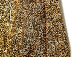 Macro shot of metallic gold and black textured fabric with a premium metal zipper detail