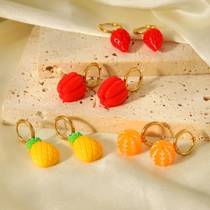 Detailed shot of fruit-shaped earrings including strawberry and orange on stone