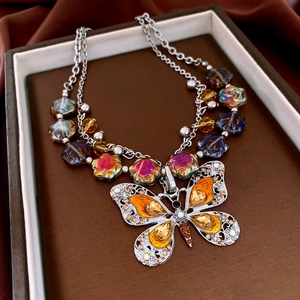 Detailed close-up of vintage butterfly pendant with amber crystals and glass beads
