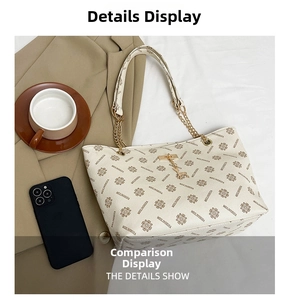 Detail of beige tote bag with monogram print, metal chain strap and deer head pendant