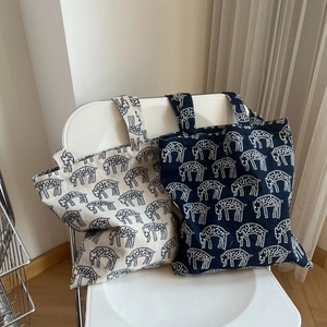 Detail of embroidered canvas tote bags with animal prints on a minimalist chair