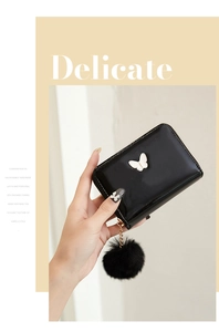 Close-up of black patent leather mini purse with white bow and plush ball detail