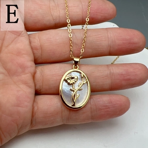 Detailed close-up of golden oval pendant with white mother of pearl and floral motif