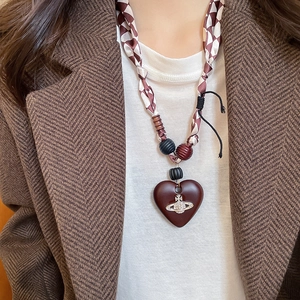 Detailed close-up of retro heart pendant necklace featuring beaded cord and silver orb motif