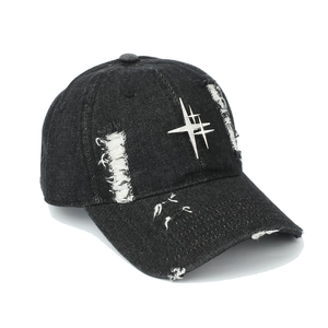 Detail of distressed black denim baseball cap with silver metal star rivet accents