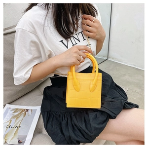 Detail shot of yellow crocodile pattern handbag with chain strap styled on a model