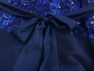 Close-up of elegant dark blue floral chiffon dress with a decorative bow neckline detail