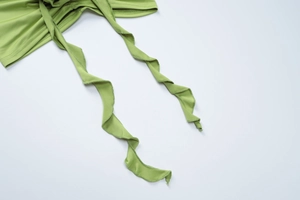 Detailed view of light green ruched fabric with ruffle trim and adjustable drawstring ties