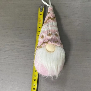 Dettaglio di uno gnomo natalizio in maglia rosa da 19 cm con metro a nastro di riferimento