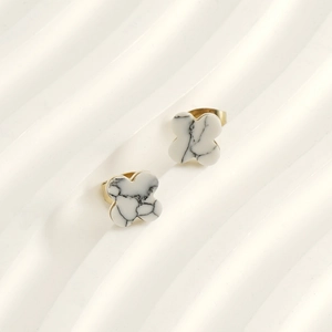 Detail of four-leaf clover stud earrings featuring white marble inlay and gold-tone edges