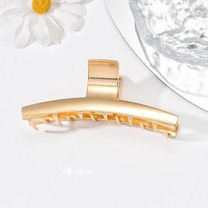 Minimalist gold metal hair claw clip with sleek curved design on clean white background