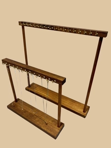 Detailed view of two dark brown wooden necklace display stands with metal hooks and base