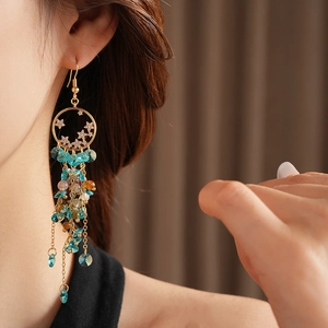 Vintage star tassel earrings with blue crystals and pearls shown on a model