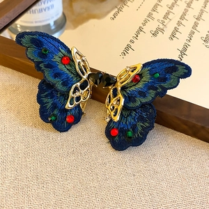 Detail of vintage blue embroidered butterfly hair clip with colorful rhinestones on fabric