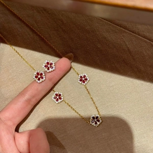Gold plated necklace featuring five red zircon flower pendants with white crystal centers