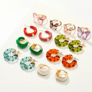 Macro detail of various colorful resin C-shape hoop earrings and butterfly rings