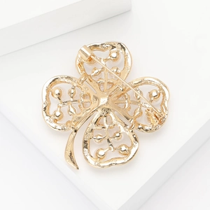 Detail view of the golden metal hollow four-leaf clover brooch back with pin closure