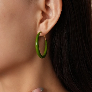 Primo piano di una modella che indossa orecchini a cerchio geometrici in resina verde