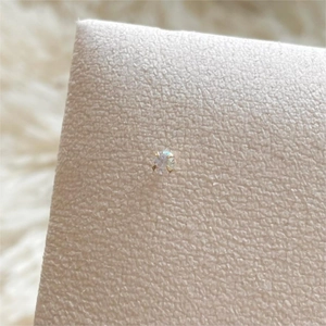Close-up of four-prong round cut diamond stud earring on a beige leather display stand