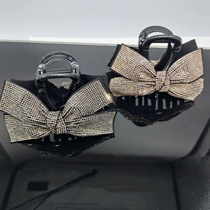 Detailed close-up of two elegant black bow hair claws with sparkling rhinestones