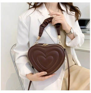 Detail view of heart-shaped dark brown leather crossbody bag with pleated handle