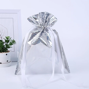 Close-up of silver laser holographic drawstring gift bag with honeycomb texture and white ribbon
