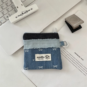 Detail einer Patchwork-Minitasche aus Denim mit weißem Schleifenstick und Reißverschluss