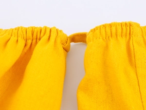 Detail of yellow cotton linen fabric showing elastic waist pleats and drawstring texture