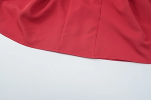 Detailed close-up showing the red dress hem stitching and smooth fabric texture