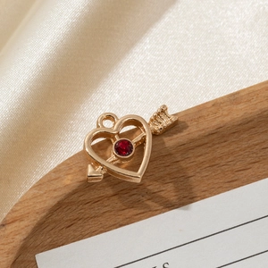 Macro shot of gold-plated heart and arrow pendant with a faceted red crystal stone