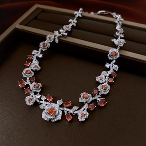 Macro shot of silver vintage rose necklace featuring orange red zircon stones in detail