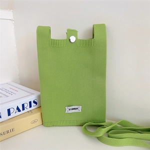Detail of green knitted crossbody phone bag featuring vertical texture and metal snap button