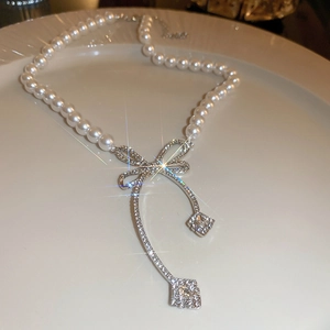 Elegant silver bow pearl choker necklace with sparkling rhinestones on a white plate