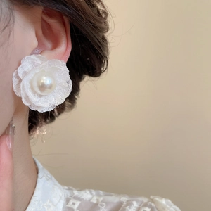 Primo piano di eleganti orecchini a fiore in tulle e perle indossati da una modella