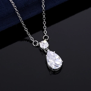 Détail d'un collier argenté avec des cristaux en forme de poire sur fond bleu foncé profond